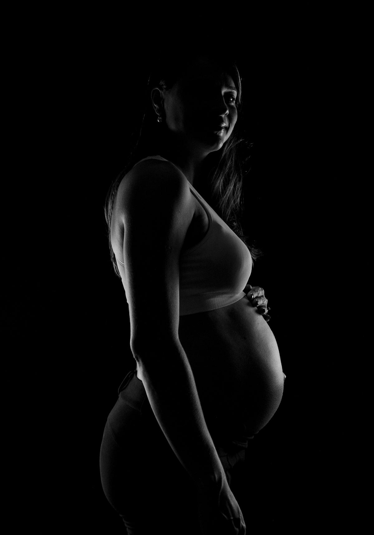 grayscale photo of pregnant woman near black surface